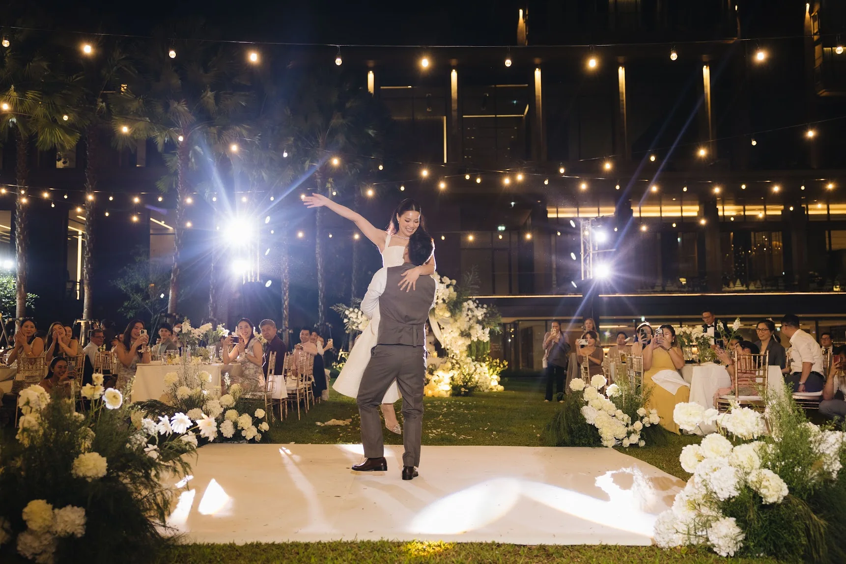 Groom speaking beneath the reception lights at the Annie & Louis celebration in Bangkok