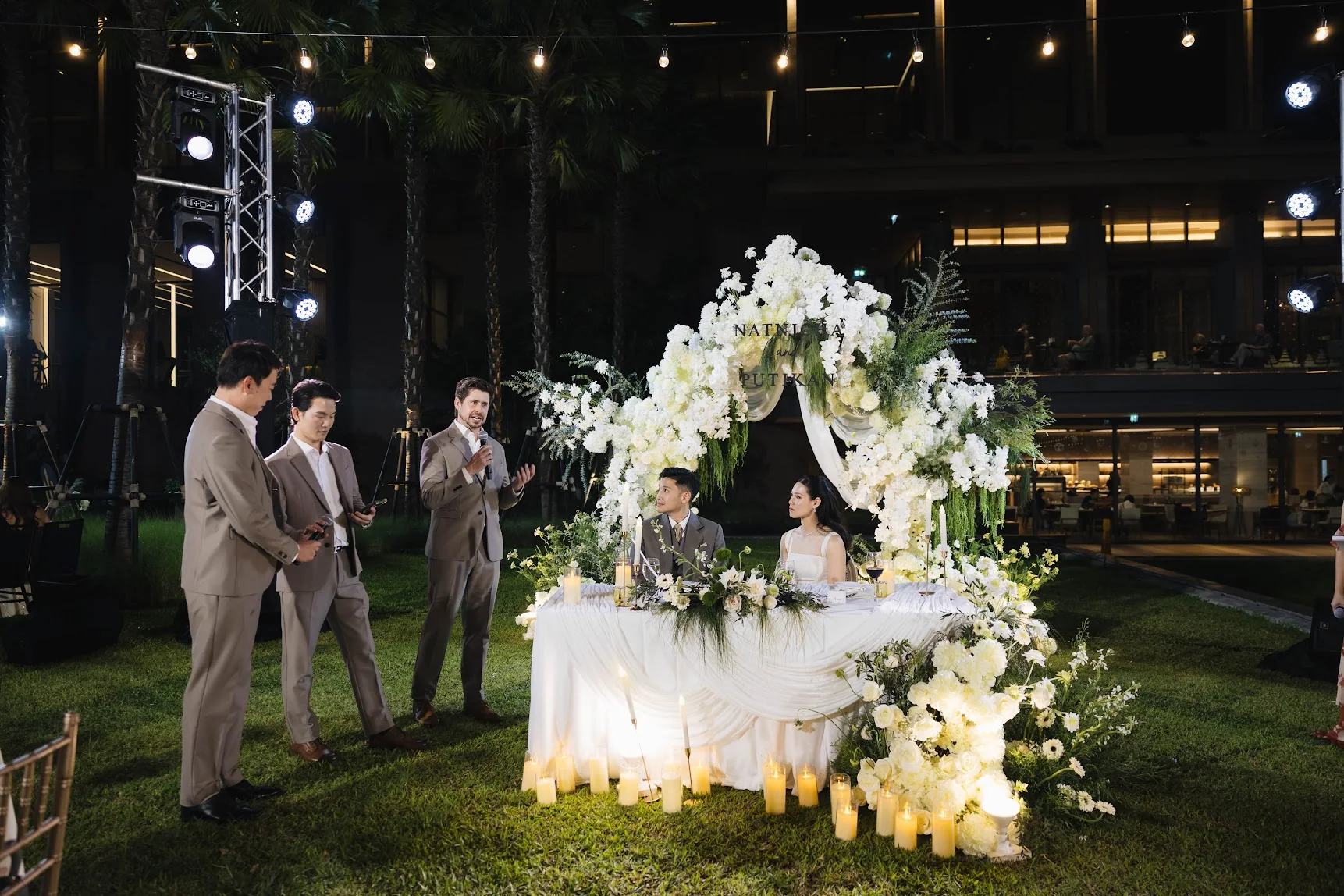 Couple beside the white floral ceremony canopy at the Annie & Louis celebration in Bangkok