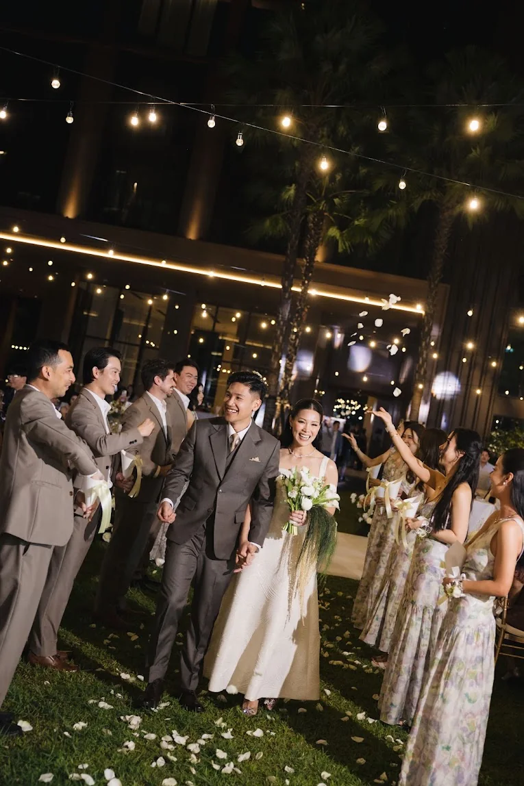 Couple walking between their guests at the Annie & Louis celebration in Bangkok