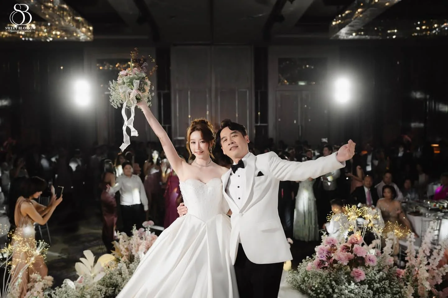 Couple celebrating on the pastel floral stage at the Orm & Fuse celebration in Bangkok