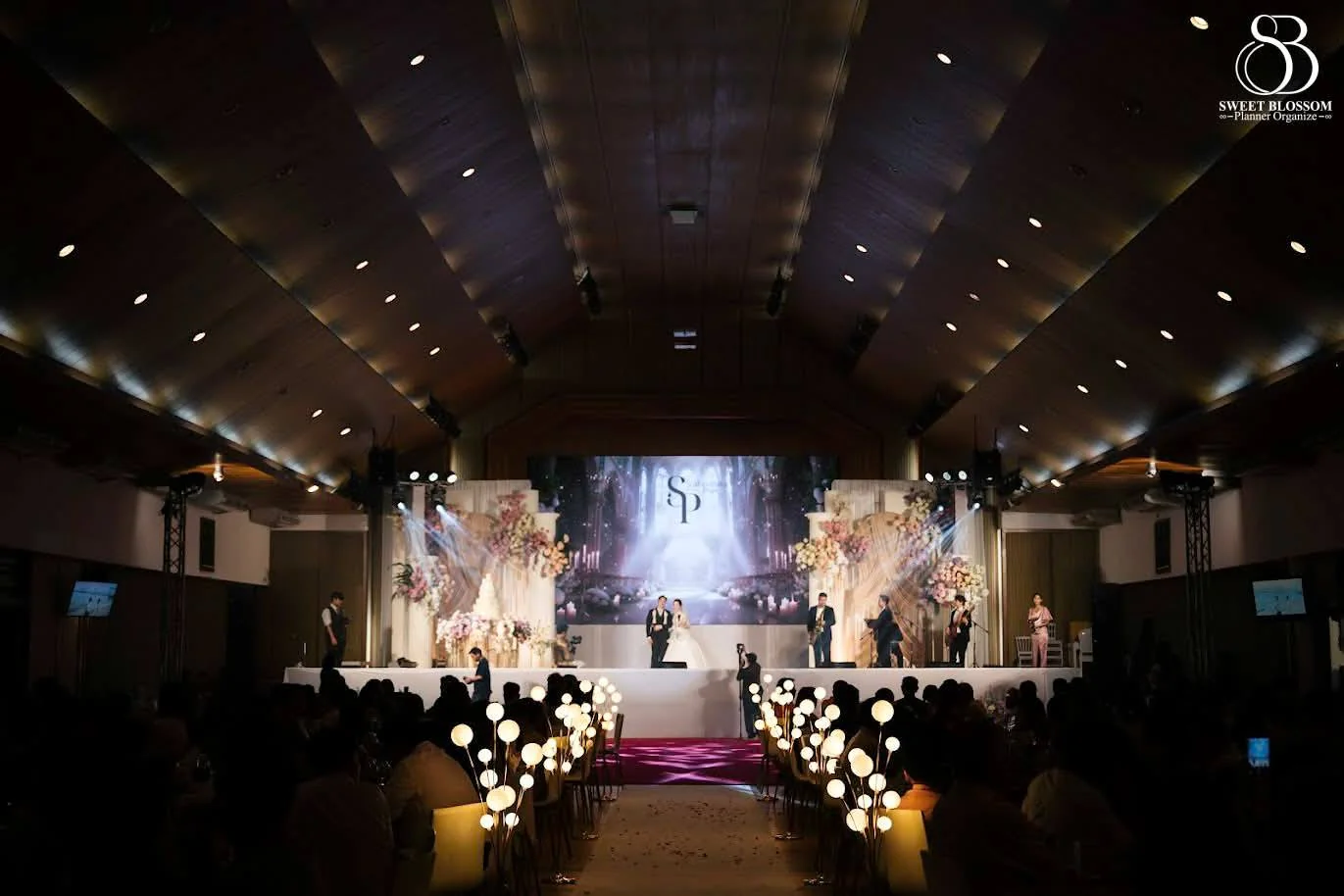 Wide view of the ballroom aisle and wedding stage at the Foam & Petch celebration in Lopburi