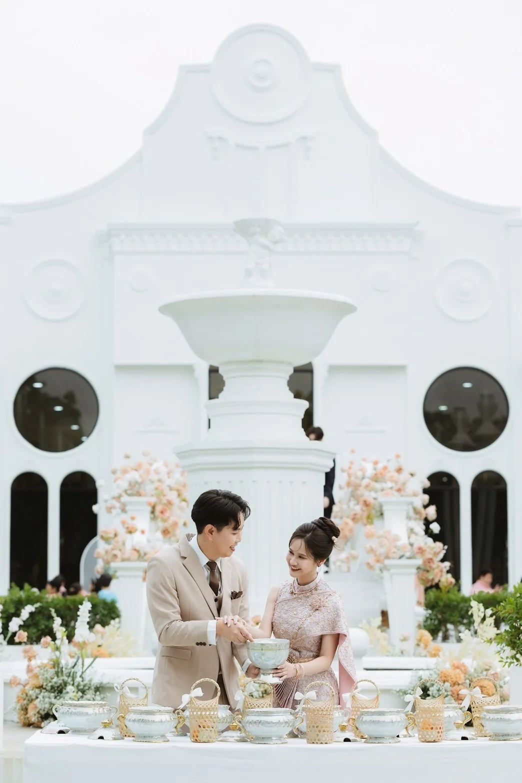 Couple at the outdoor ceremony table beside the white chapel at the Jah & Peet celebration in Lopburi
