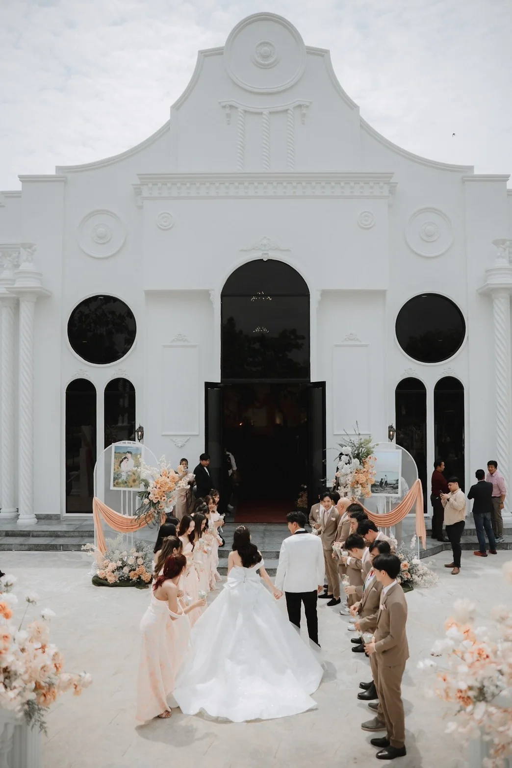 Couple walking toward the white chapel at the Jah & Peet celebration in Lopburi