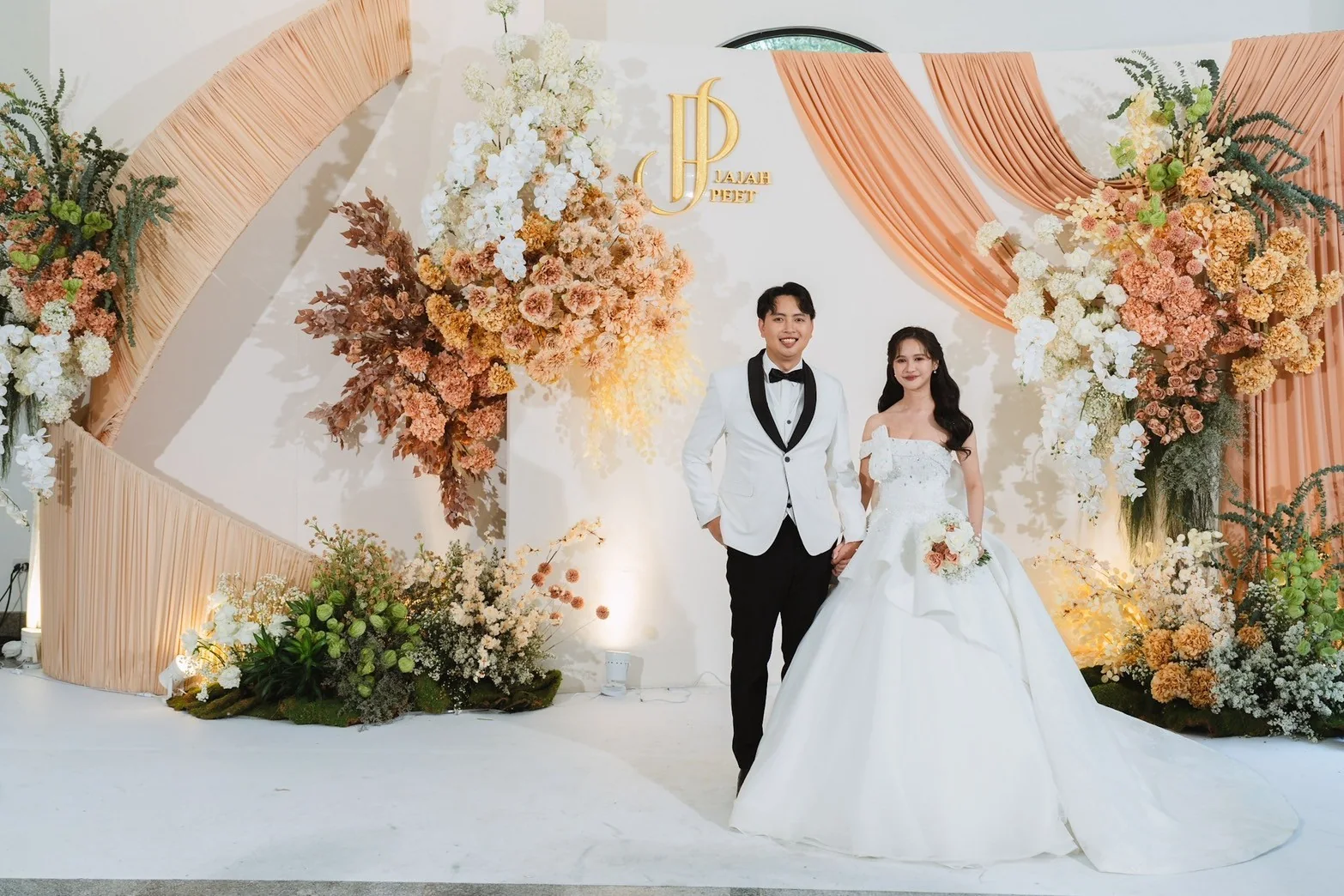 Couple portrait at the warm floral wedding stage at the Jah & Peet celebration in Lopburi