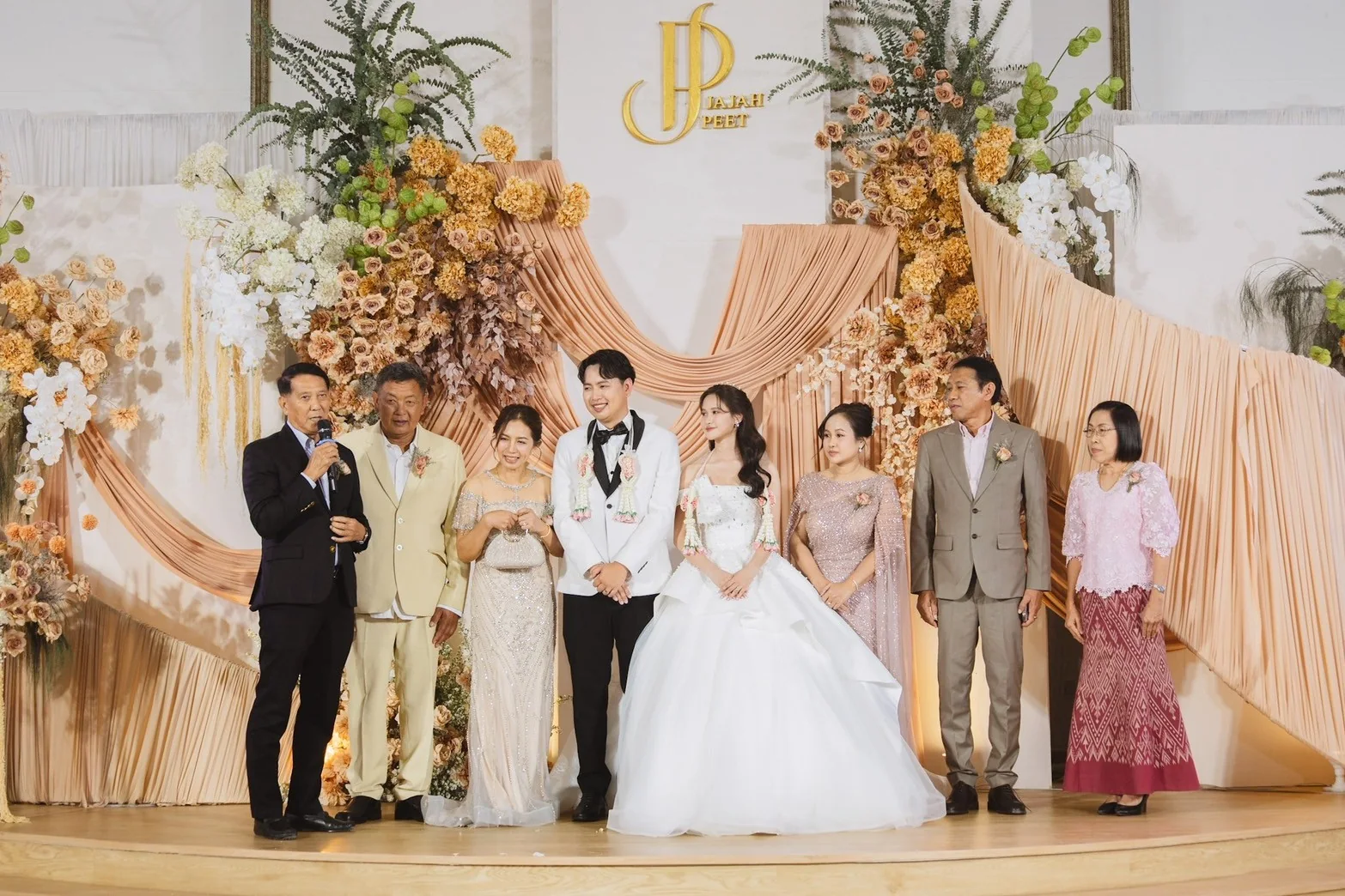 Couple and family portrait at the wedding stage at the Jah & Peet celebration in Lopburi