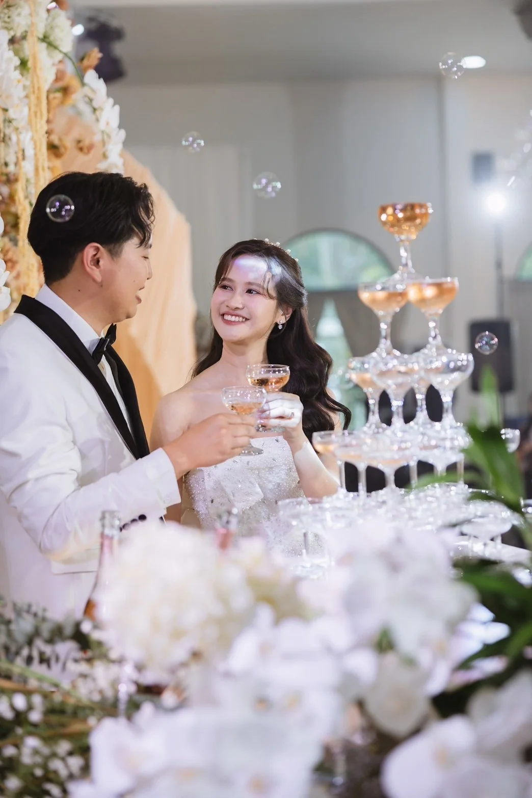 Couple beside the champagne tower at the Jah & Peet celebration in Lopburi