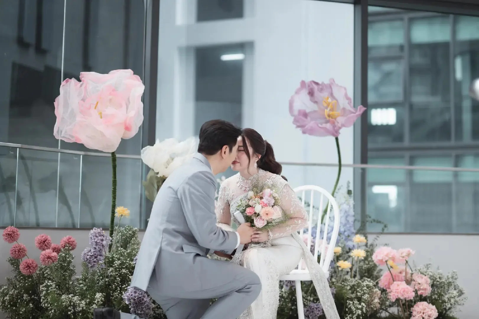 Couple sharing a quiet moment beside pastel flowers at the Jum & Jai celebration in Chonburi