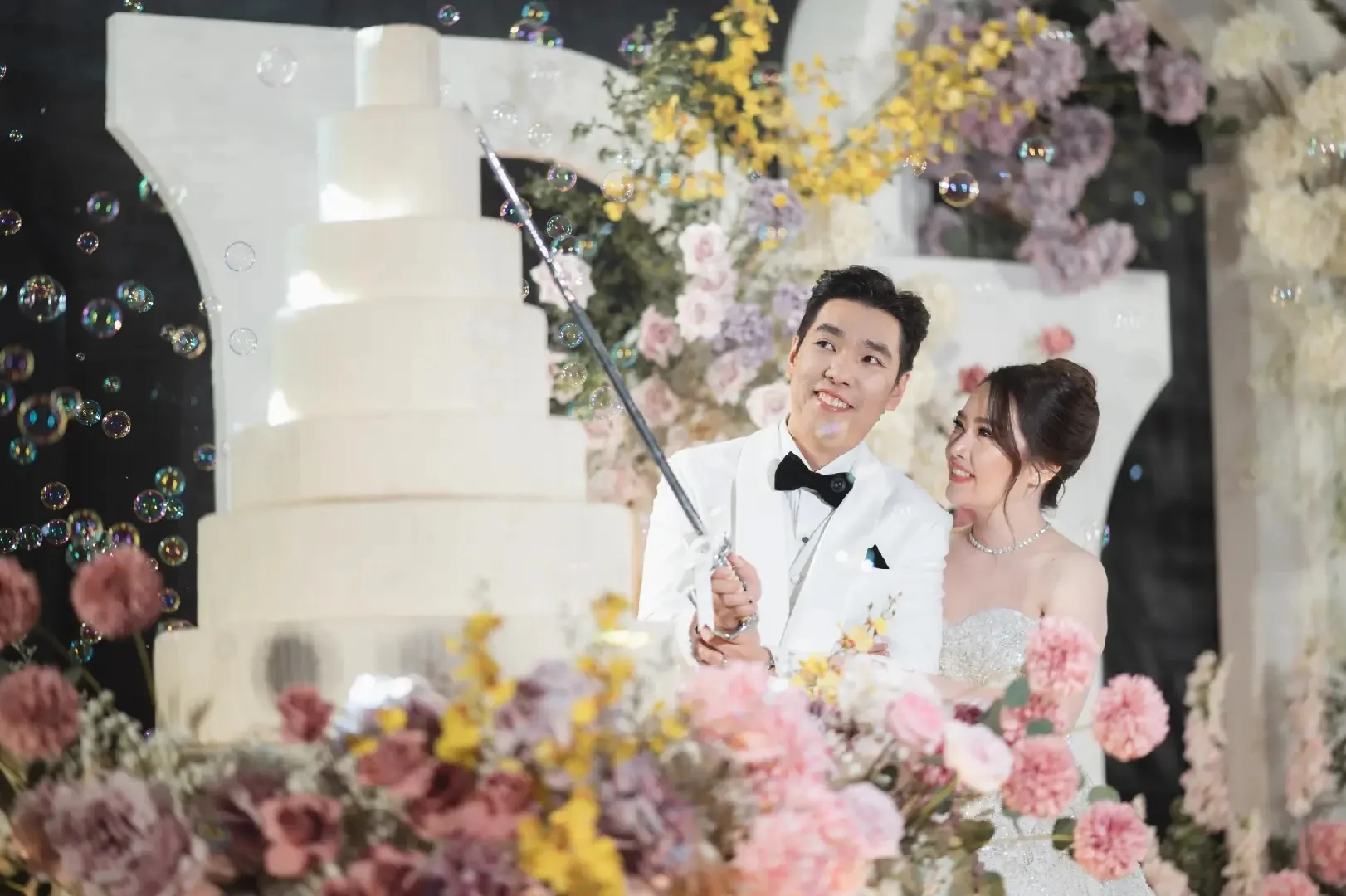 Couple taking a playful selfie beside the cake at the Jum & Jai celebration in Chonburi