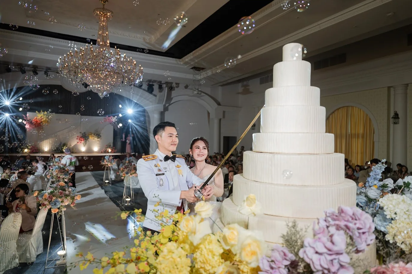 Couple beside the wedding cake at the Koko & Raam celebration in Chonburi