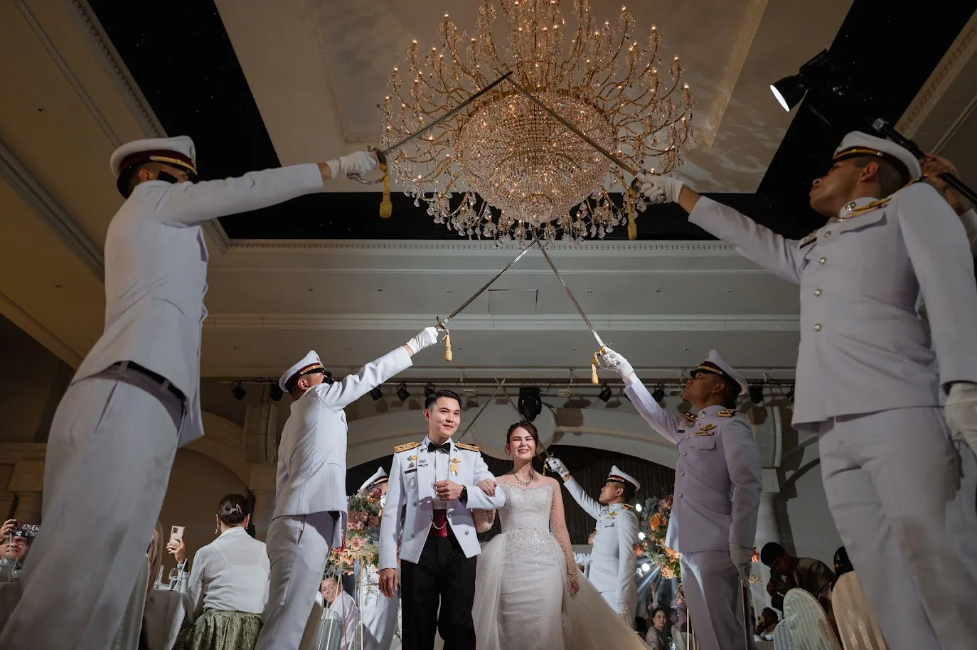 Ceremonial sword arch above the couple at the Koko & Raam celebration in Chonburi