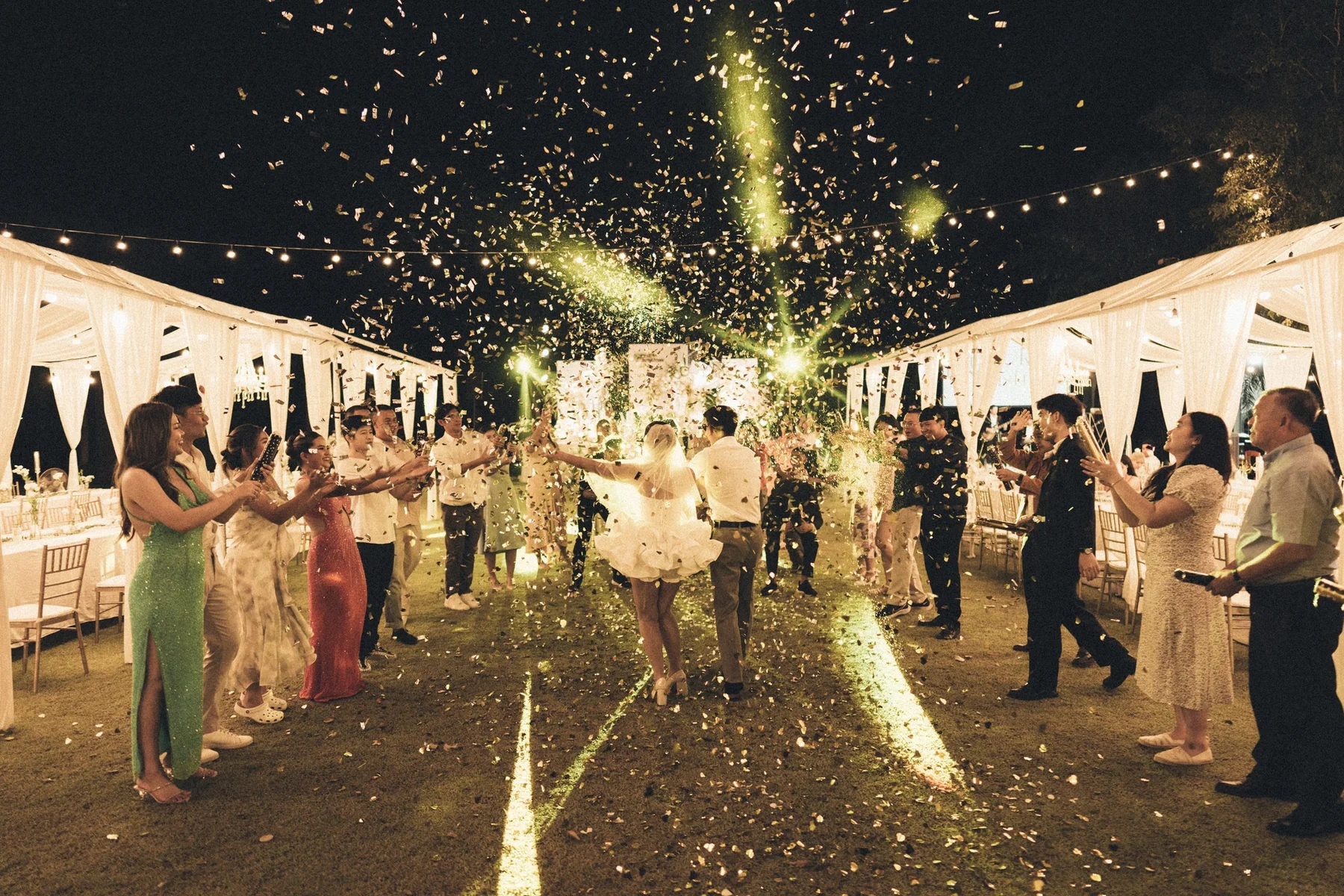 Couple entering the outdoor reception beneath sparklers at the Mook — Christmas Wedding celebration in Lopburi