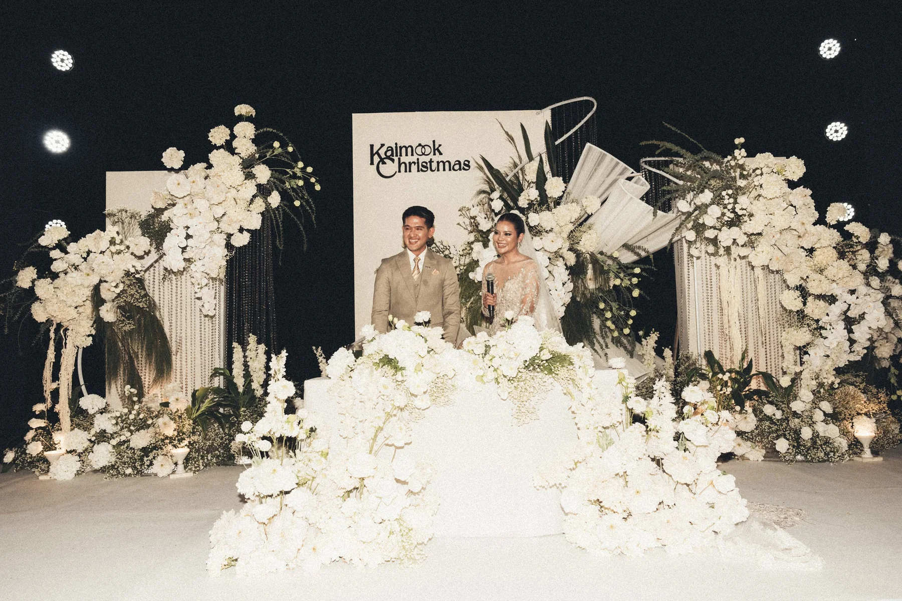 Couple behind the white floral ceremony table at the Mook — Christmas Wedding celebration in Lopburi