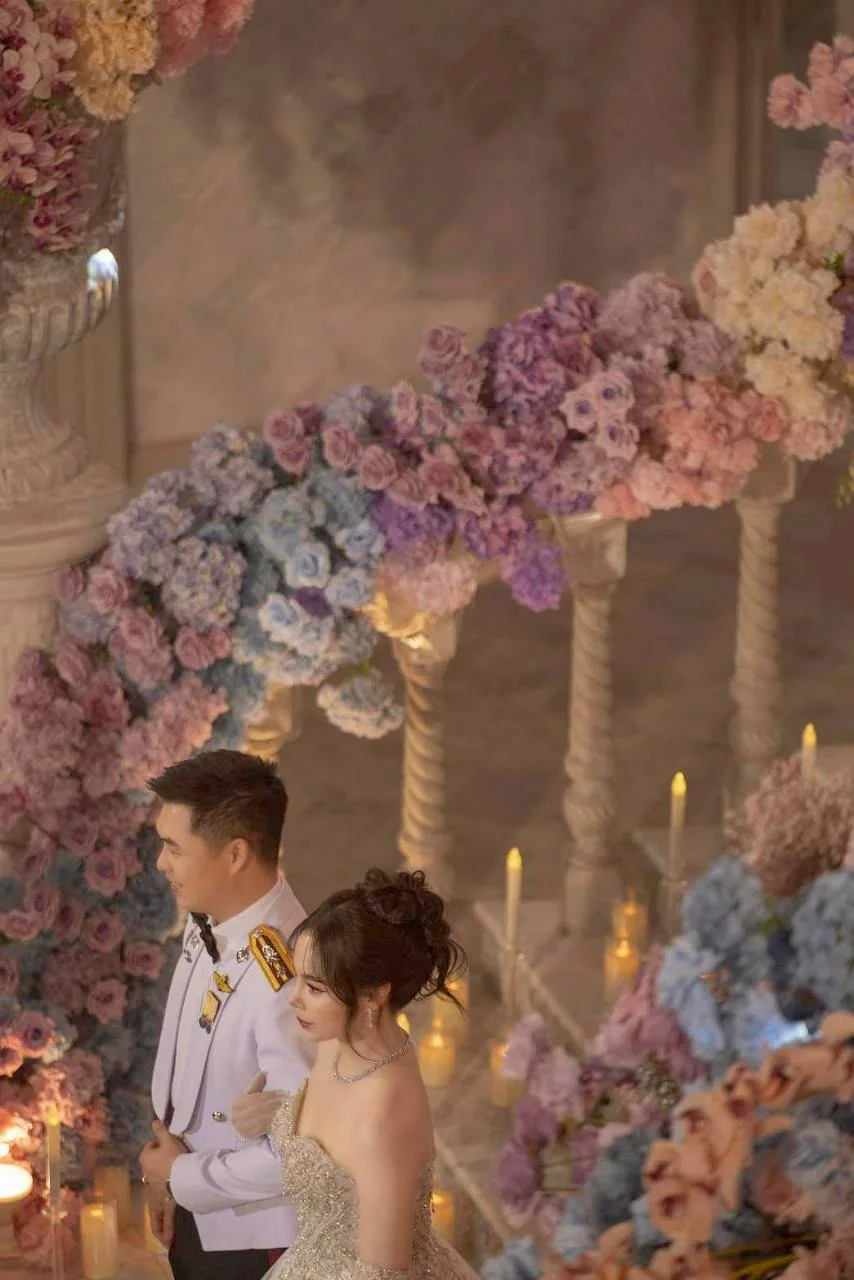 Couple seated behind the pastel floral reception arrangement at the Nan & Big celebration in Bangkok