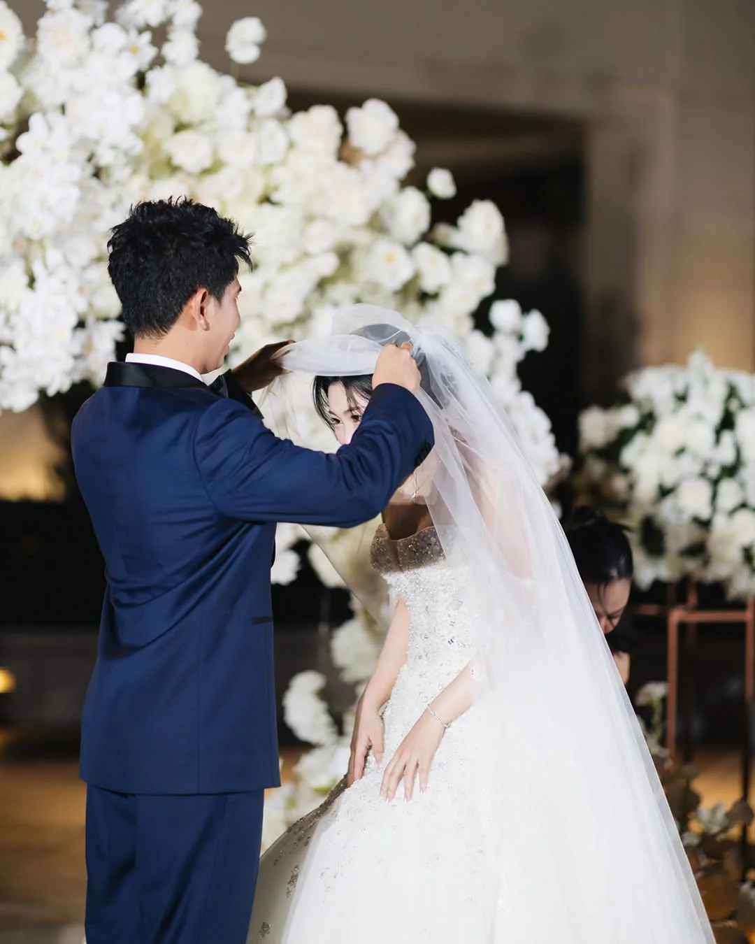 Groom adjusting the bride's veil during the ceremony at the Natt & Yang celebration in Bangkok