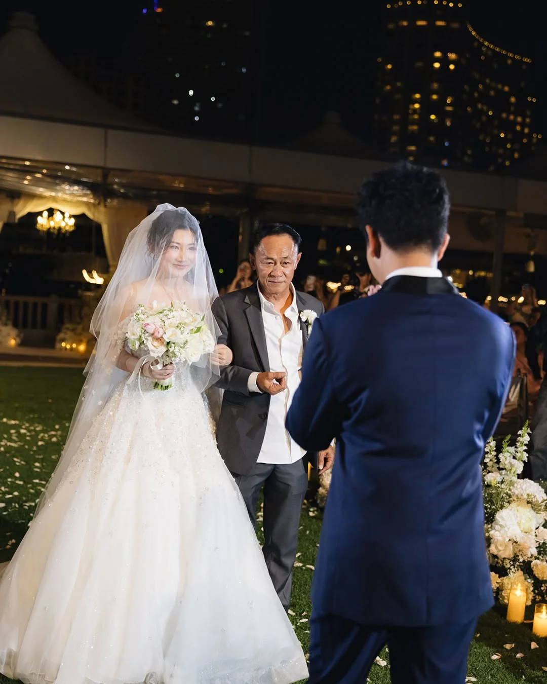 Bride approaching the groom with her family at the Natt & Yang celebration in Bangkok