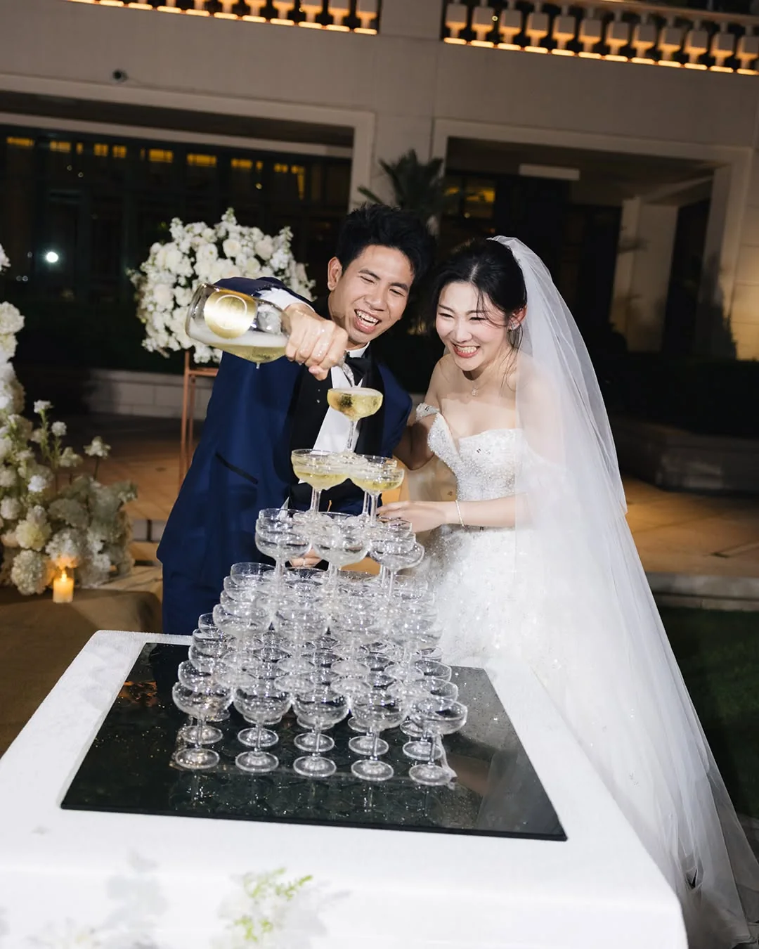 Couple pouring the champagne tower at the Natt & Yang celebration in Bangkok