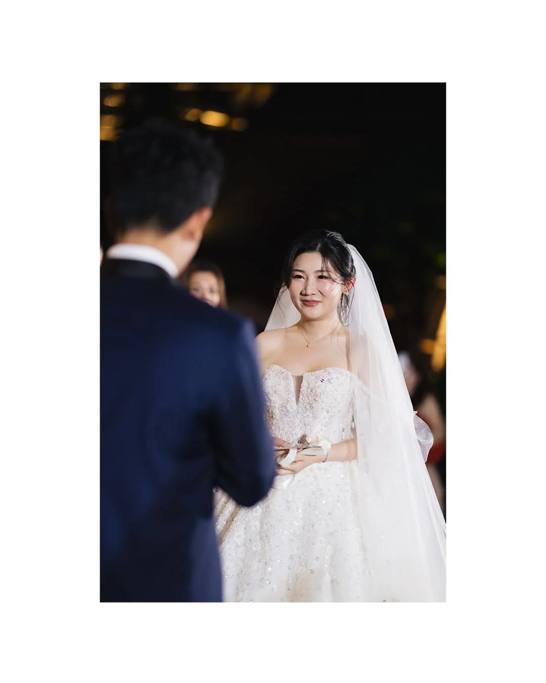Bride smiling toward the groom at the Natt & Yang celebration in Bangkok