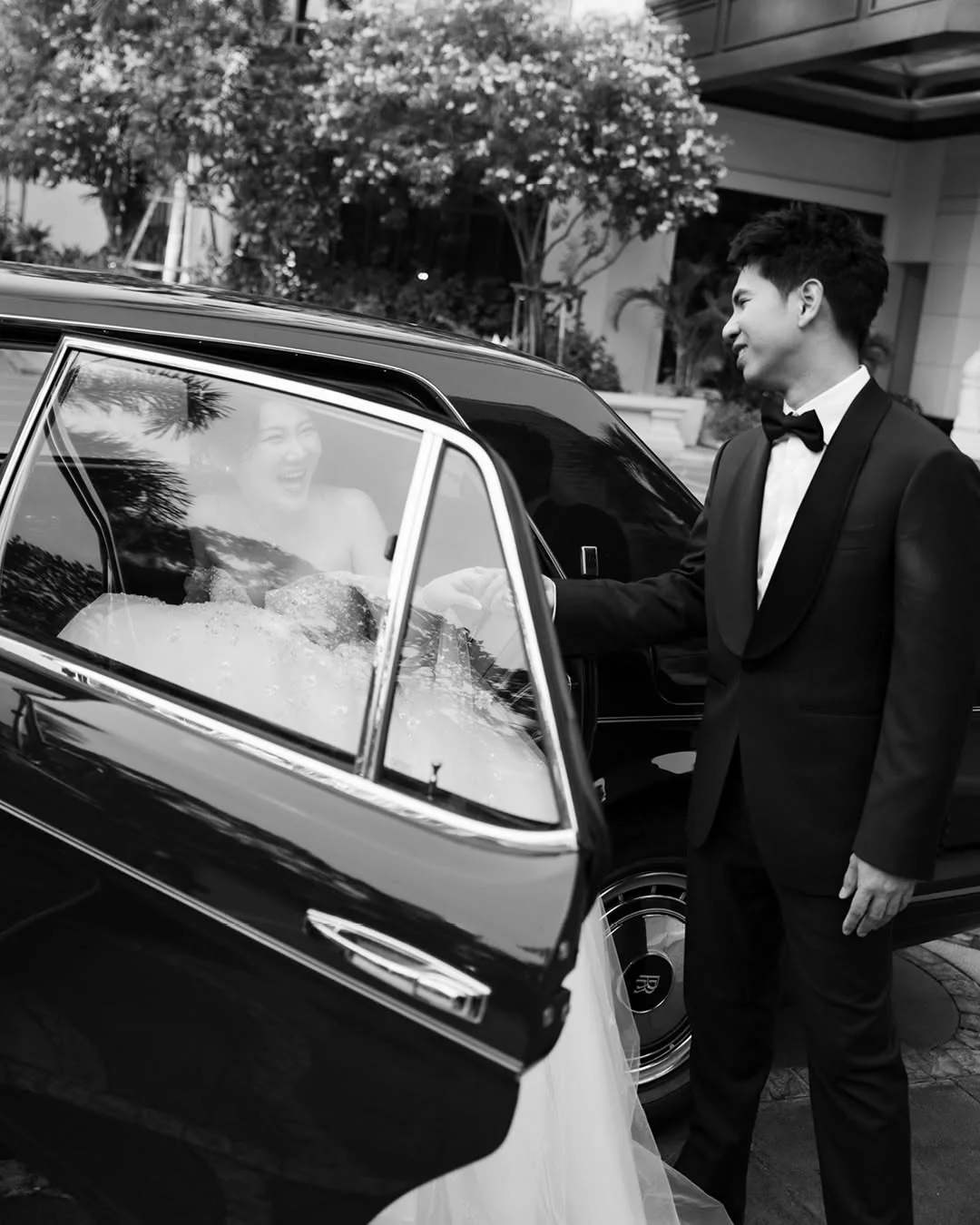 Black-and-white portrait beside a classic car at the Natt & Yang celebration in Bangkok
